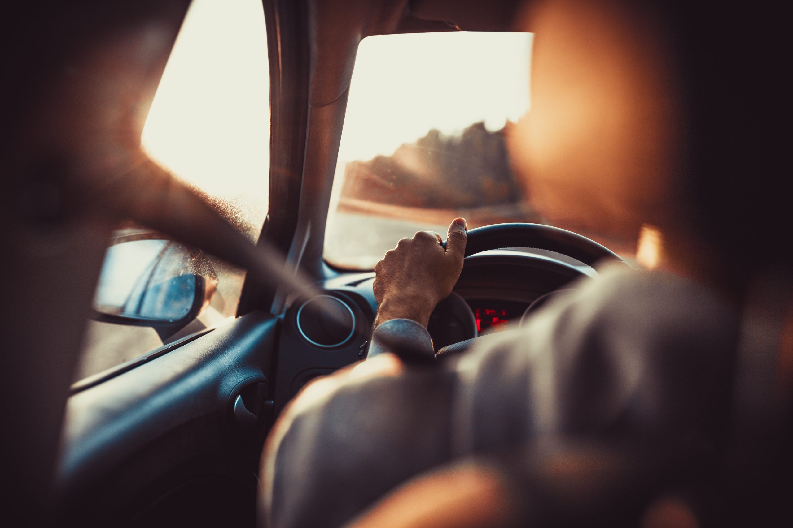 Man driving car, hand on steering wheel, looking at the road ahead