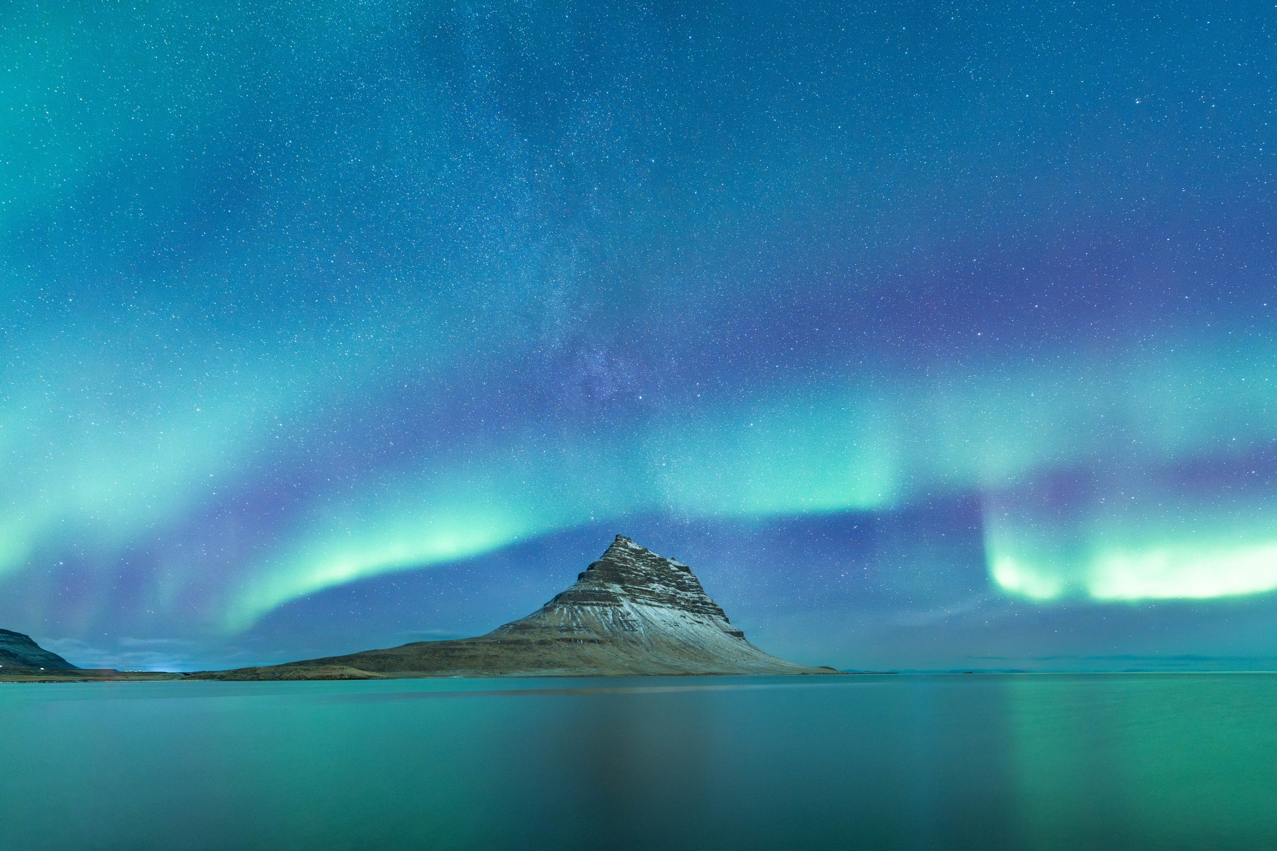 Kirkjufell mountain with northern lights and the milky way behind it. Kirkjufell mountain on the Snæfellsnes peninsula in Iceland.